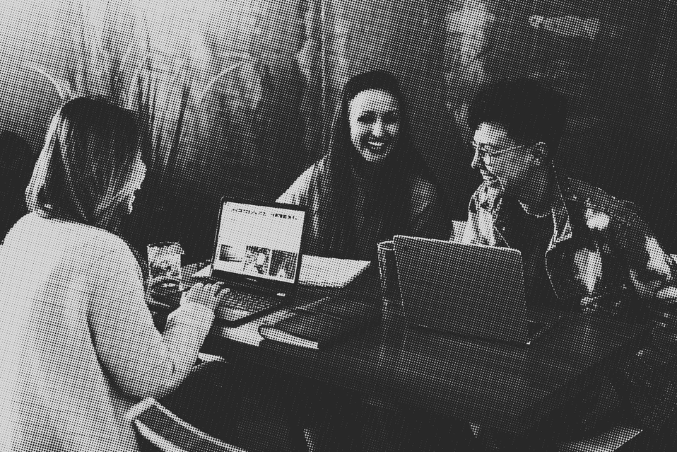 Friends laughing while working in a cafe with their laptops